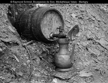 Photo en noir-blanc d'un fût de vin qui remplit une channe