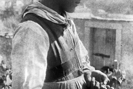 Photo en noir-blanc d'une femme en habits traditionnels valaisans récoltant du raisin