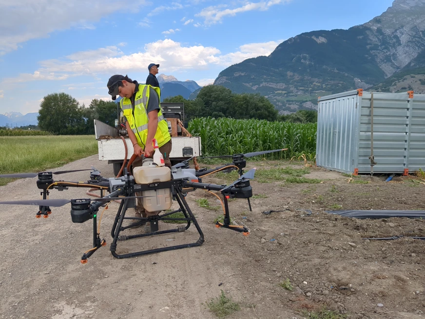 Un jeune viticulteur remplit un drone d'épandage dans une zone agricole en Valais