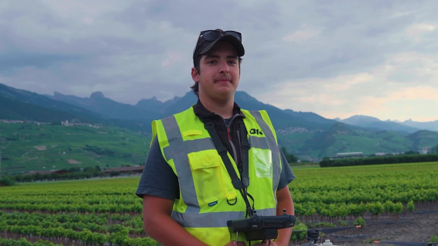 Timéo Bétrisey - Apprenti viticuleur devant une pépinière viticole avec une manette de drone autour du cou